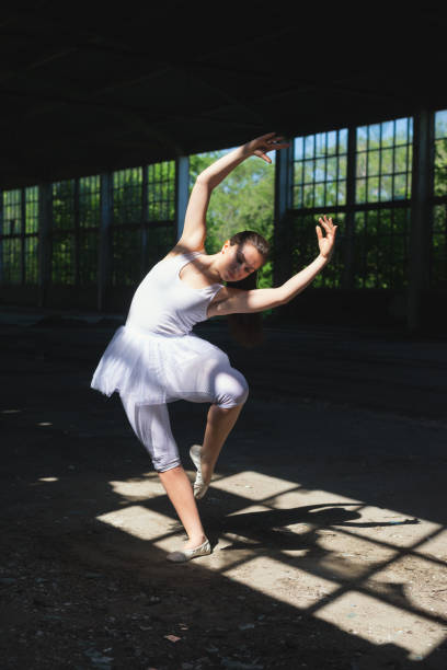 istock Ballerina in white dancing in abandoned building 954358824