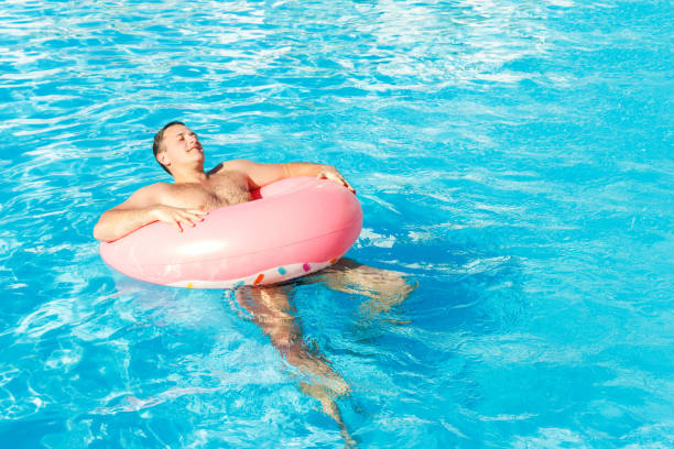 istock Beautiful young man relaxing near pool. vacation concept with space for text. Top view 954362110