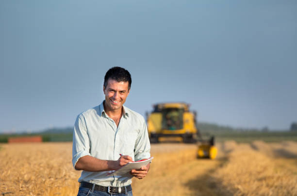 istock Engineer with note book and combine harvester in field 954362562