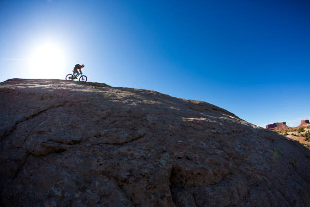 Mountain Bike Moab Utah A man rides a popular slickrock trail near Moab, Utah at the end of the day. He is riding a cross-country enduro style bike and is wearing a hydration backpack. slickrock trail stock pictures, royalty-free photos & images