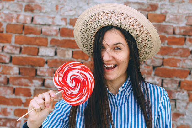 istock Young happy female with hat and candy or lollipop 954375406