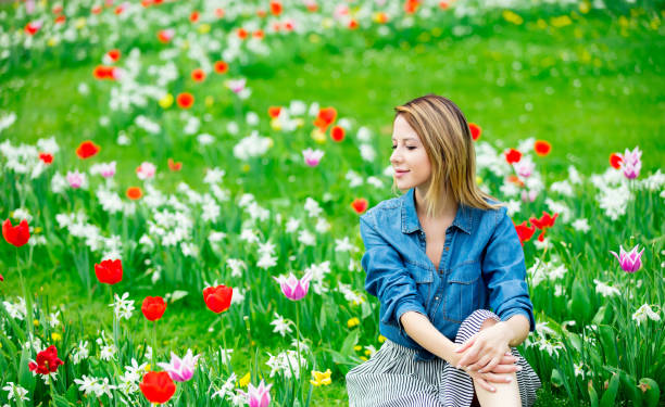 istock Young redhead girl sitting at tulips meadow 954384834