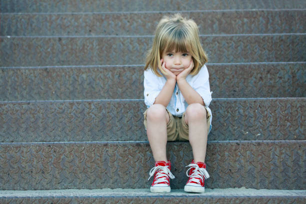 triste garçon assis sur l’escalier - little boys child sadness depression photos et images de collection