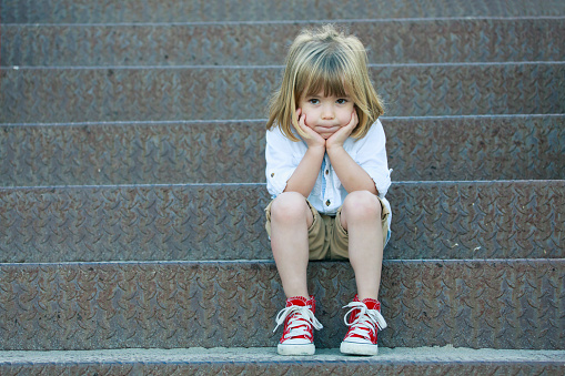 Sad little boy sitting on staircase.