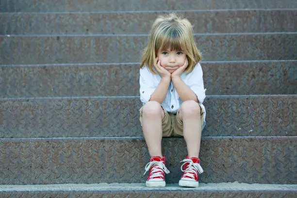 Sad little boy sitting on staircase.