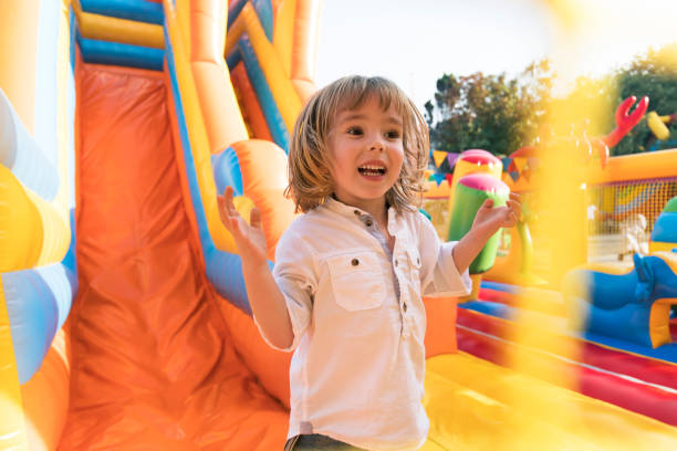 little kid having fun in inflatable castle playground - inflatable child jumping leisure games imagens e fotografias de stock