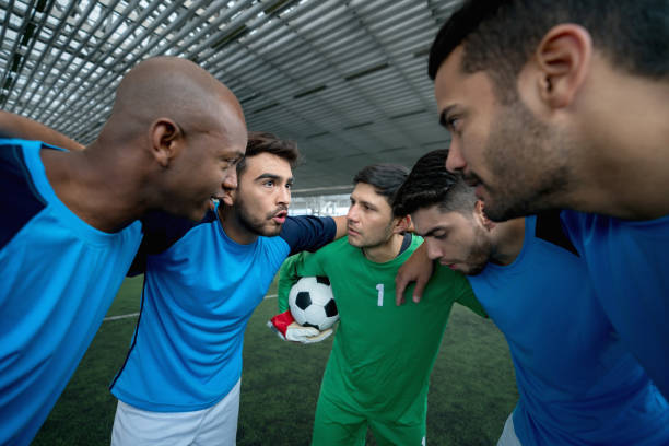 Male indoor soccer team on a huddle talking before starting the game