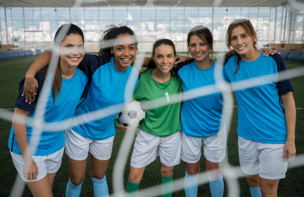 istock Professional soccer players standing behind the net looking at camera smiling 954392558