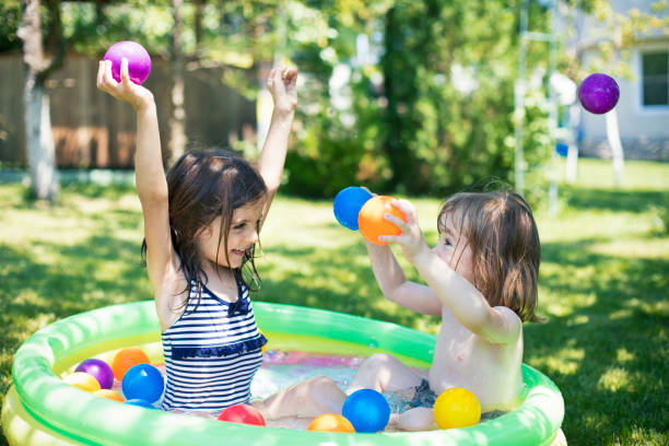 Two cute children having fun in inflatable swimming pool.