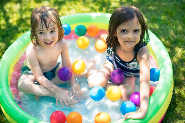 Two cute children having fun in inflatable swimming pool.
