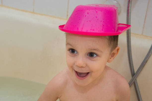 The boy plays and laughs in the bathtub