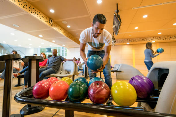 istock Young man grabbing a bowling bowl to play 954411502