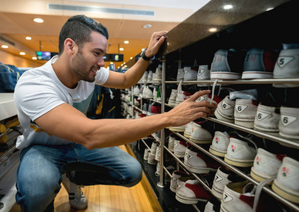 Close up of the bowling balls with Asian millennial woman getting ready to roll the bowling ball, concentrating at the edge of bowling alley.