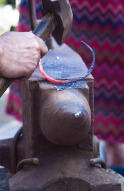 istock blacksmith performs the forging of hot glowing metal on the anvil 954413806