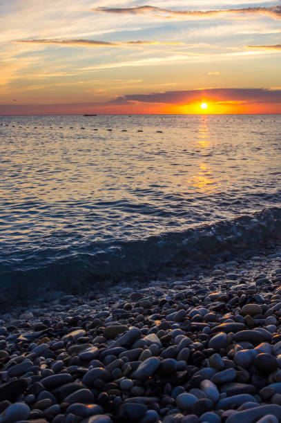 istock Amazing sea sunset on the pebble beach, the sun, waves, clouds 954418046