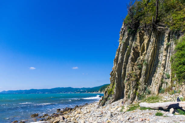 istock rocky sea shore with pebble beach, waves with foam 954427322