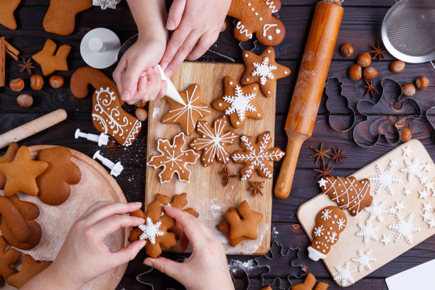 istock Christmas bakery. Friends decorating freshly baked gingerbread c 954428492