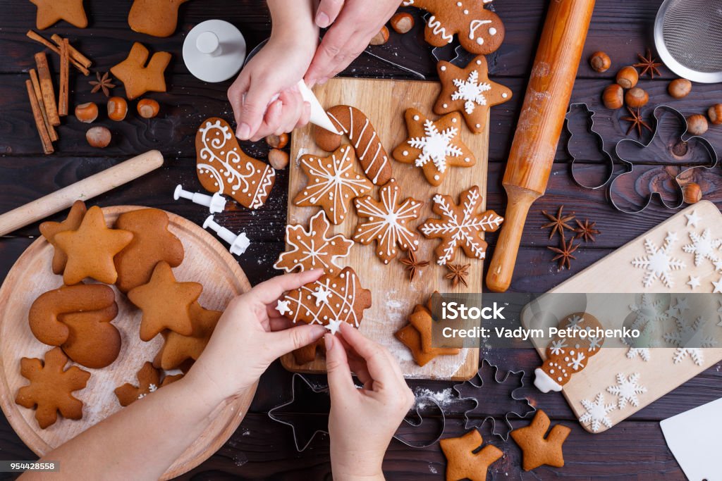 Christmas gingerbread making. Friends decorating freshly baked c Christmas gingerbread making. Friends decorating freshly baked cookies with icing and confectionery mastic, view from above. Festive food, family culinary, Christmas and New Year traditions concept Cookie Stock Photo