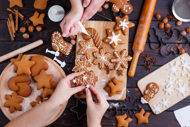 Christmas gingerbread making. Friends decorating freshly baked c Christmas gingerbread making. Friends decorating freshly baked cookies with icing and confectionery mastic, view from above. Festive food, family culinary, Christmas and New Year traditions concept decorating a cake photos stock pictures, royalty-free photos & images