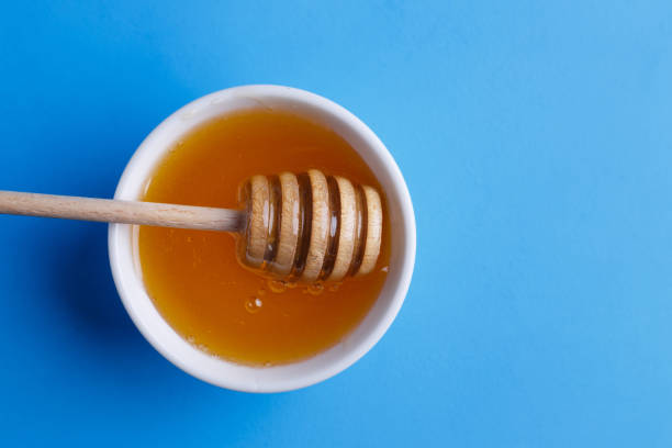 istock Honey with wooden honey dipper on blue background, view from abo 954438984