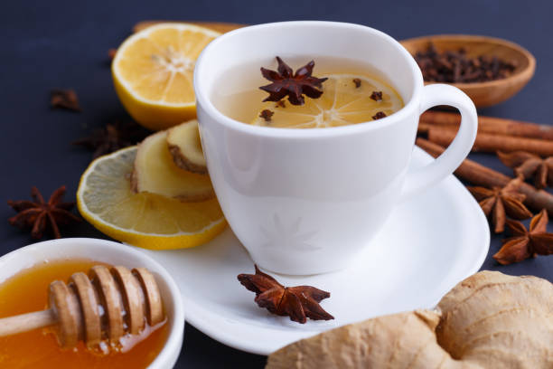 istock Close up of a cup with ginger tea and ingredients on dark table. 954442038