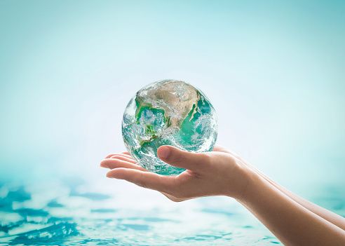 World ocean day, saving water campaign, sustainable ecological ecosystems concept with green earth on woman's hands on blue sea background : Element of this image furnished by NASA