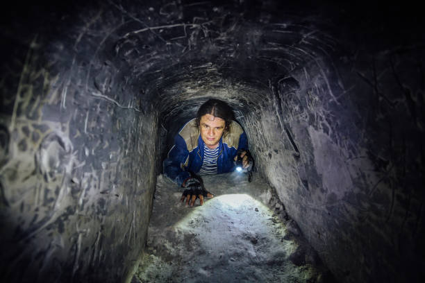man explores narrow passage in ancient abandoned underground chalky cave monastery - claustrophobic imagens e fotografias de stock