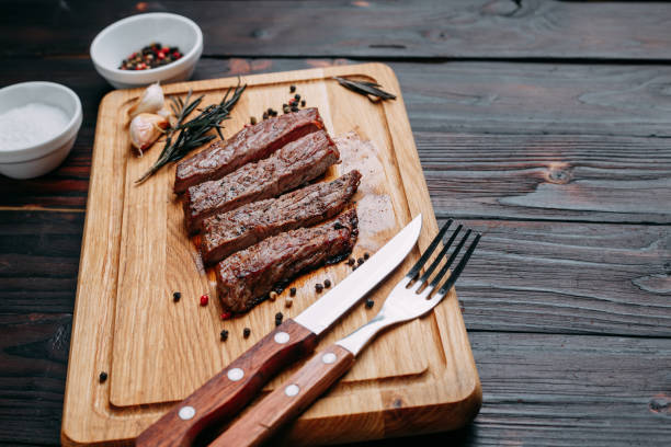 istock Sliced well-done grilled beef steak on wooden cutting board with 954466032