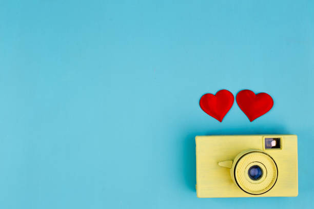 istock Two red fabric hearts and yellow vintage camera on blue backgrou 954474618