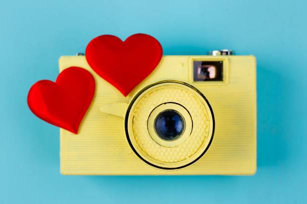 istock Two red fabric hearts and yellow vintage camera on blue backgrou 954474930