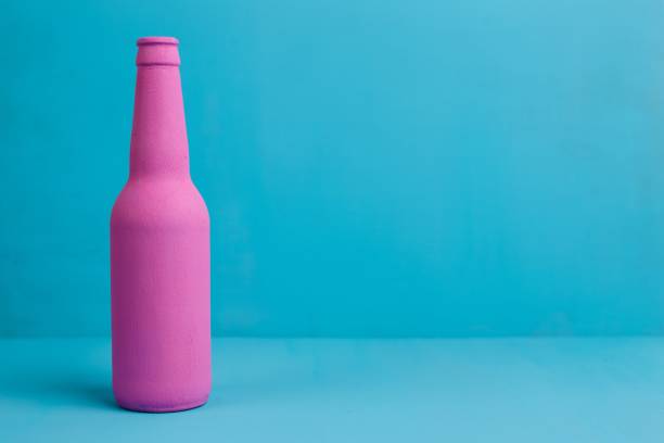 istock Nice pink beer bottle on blue background. Deceptive attraction o 954475284