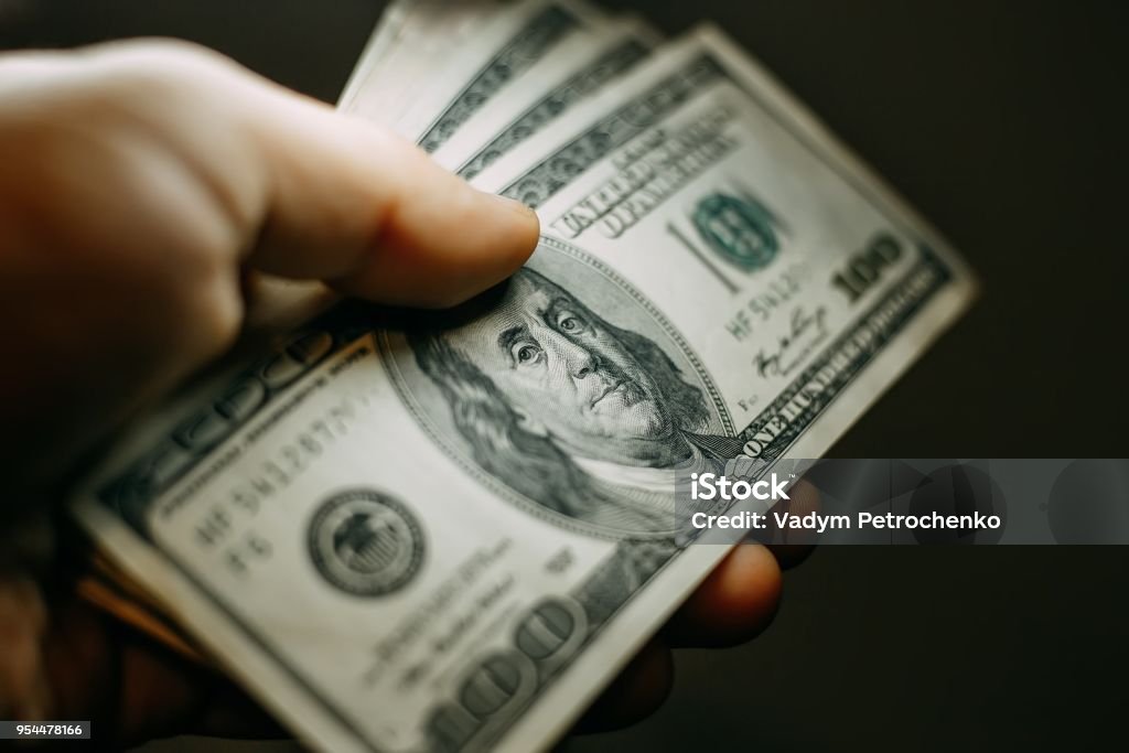 Man hand with a stack of hundred US dollars bills, close up US Paper Currency Stock Photo