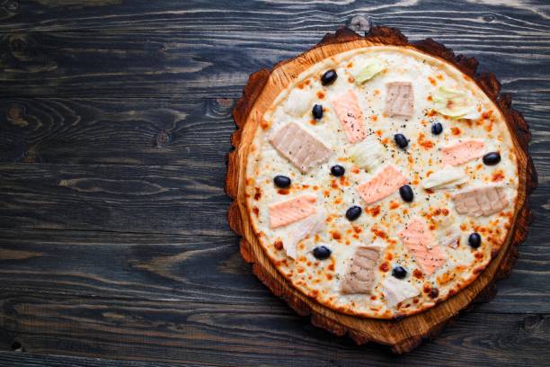 deliciosa pizza com salmão, atum e azeitonas na vista superior, madeira. - pizza tuna prepared fish cheese - fotografias e filmes do acervo