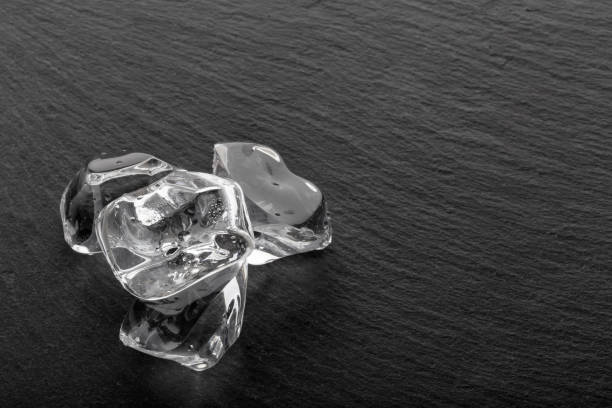 Large ice cubes with droplets on black slate board