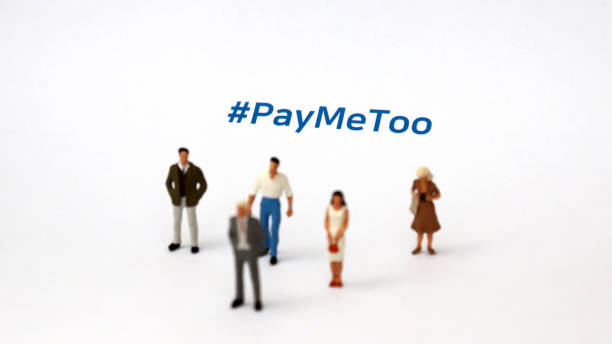 #paymetoo jako nowa kampania mająca na celu wypełnienie różnicy w wynagrodzeniach kobiet i mężczyzn. miniaturowy mężczyzna i miniaturowa kobieta stojąca na kartce papieru z #paymetoo na nim. - gender symbol human gender male sexual issues zdjęcia i obrazy z banku zdjęć