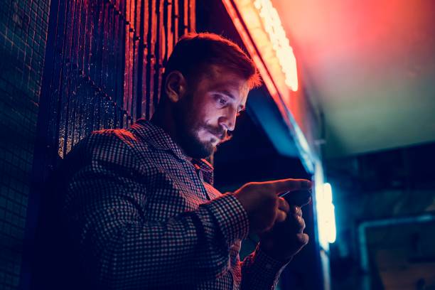 istock Closeup of a man using mobile phone in the dark with long exposure light 954504706
