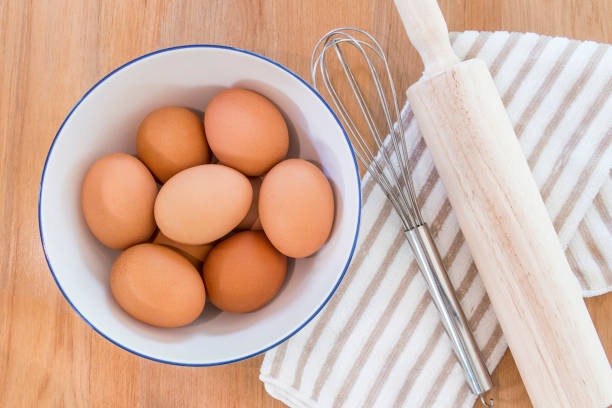 istock Baking ingredients, eggs, towel and kitchen tools on wooden table, top view 954509360