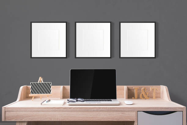 istock notebook computer and stationery on working table with blank photo frames in the studio with dark grey wall. 954509428