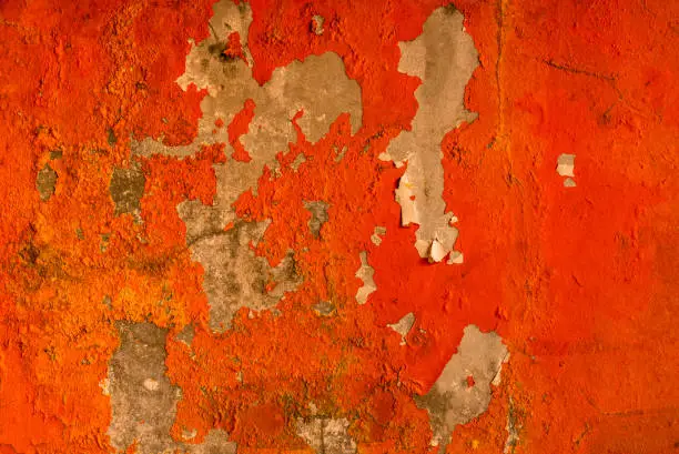 Photo of Orange color painted on concrete wall are peeling. Old and dirty wall texture background with space.