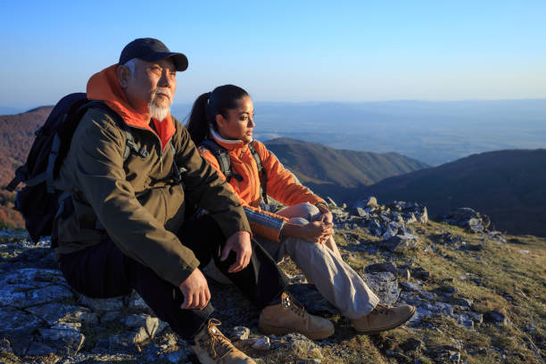 Couple backpackers sitting on top mountain and resting