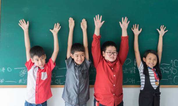 istock Group of Asian student hands up on th blackboard 954527048