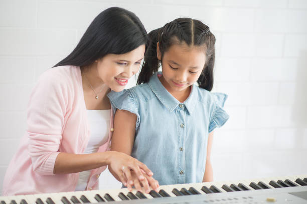 woman teacher teach piano to a gril - toddler music asian ethnicity child imagens e fotografias de stock