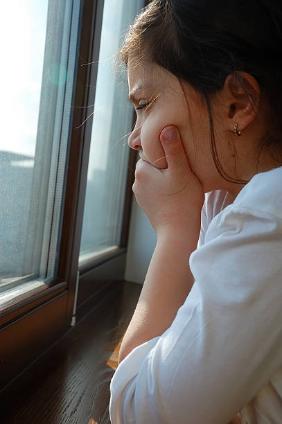 istock sad girl near a window 95452848