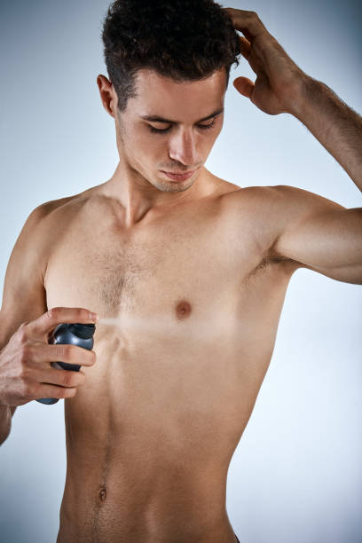 istock Muscular young man sprays armpit with deodorant 954533076