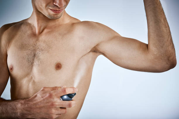 istock Muscular young man sprays armpit with deodorant 954533470