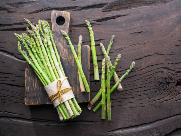 istock Green young asparagus sprouts on wooden table. 954534186