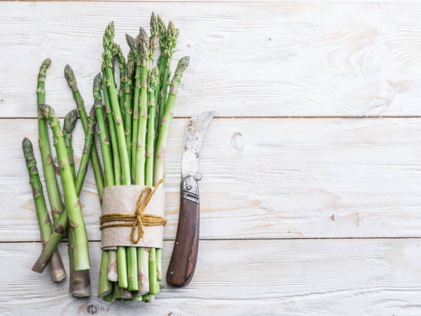 istock Green young asparagus sprouts on wooden table. 954534502