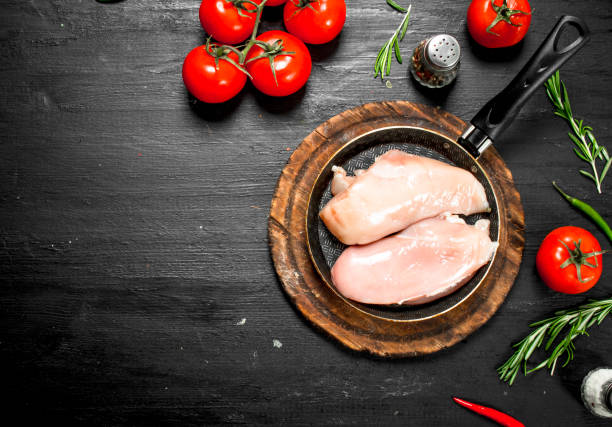 istock Raw chicken fillet with tomatoes and herbs. 954537554