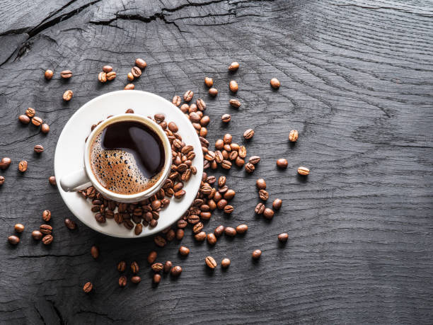 Cup of coffee surrounded by coffee beans. Cup of coffee surrounded by coffee beans. Top view. caffeine photos stock pictures, royalty-free photos & images