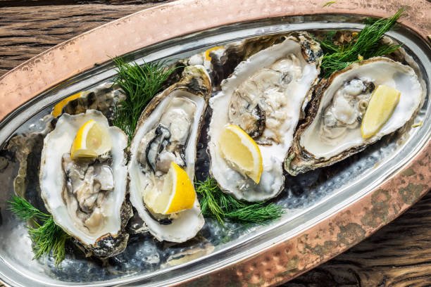 istock Opened oysters with piece of lemon. 954538260